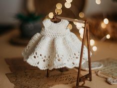 a white crocheted dress is on top of an old letter and some string lights are in the background