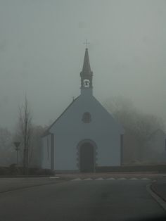 a white church with a steeple on a foggy day