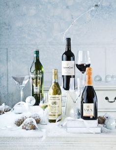 several bottles of wine and glasses on a table covered in snow, with one glass half empty