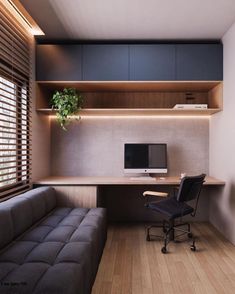 a room with a couch, desk and computer monitor on the wall next to it