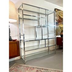 a metal shelving unit with glass shelves in the middle and a rug on the floor