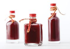 three bottles with red liquid in them on a white surface, one is empty and the other has a string tied around it