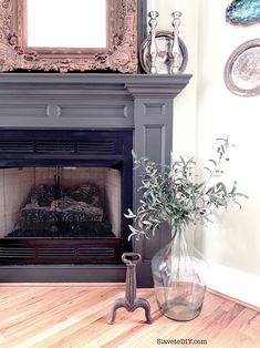 a living room with a fire place, mirror and vase on the floor next to it