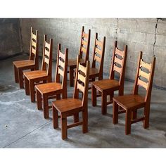 six wooden chairs are lined up against a wall in an empty room with concrete flooring