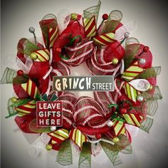 a wreath with red, green and yellow ribbons on it that says grin street leave gifts here