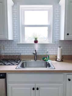 a kitchen sink with a window above it and a dishwasher on the counter