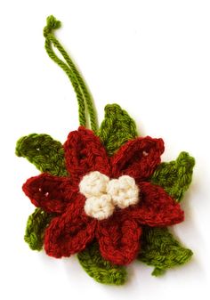 a crocheted poinsettia with leaves and flowers on it's side