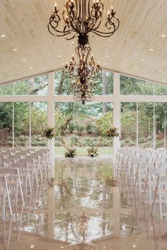 an indoor wedding venue with white chairs and chandelier