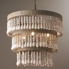 a chandelier hanging from the ceiling with beads and lights on it's sides