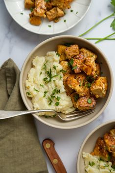 two bowls filled with chicken and mashed potatoes on top of a white tablecloth