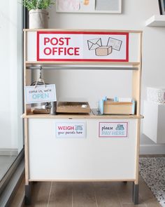 a post office sign on the side of a white wall next to a potted plant