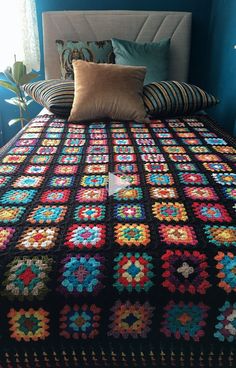 a crocheted blanket on top of a bed in a room with blue walls