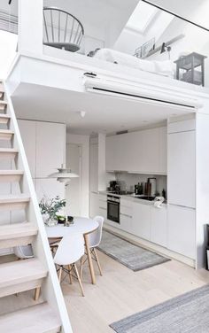 an open living room and dining area with stairs leading up to the loft bedroom above