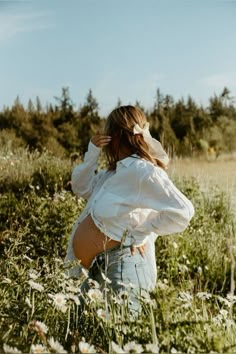 a woman standing in a field with her back to the camera