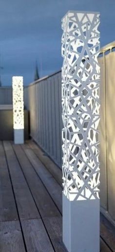 a tall white lamp sitting on top of a wooden floor next to a building wall