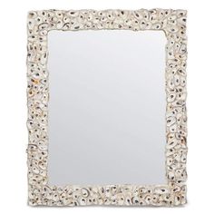 a white square mirror with shells on the edges and an ornate frame, in front of a