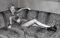 a woman laying on top of a leopard print couch