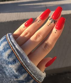 a woman's hand with red nail polish and tattoos on her fingers is shown