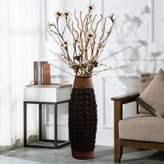 a vase with flowers in it sitting on the floor next to a chair and table