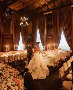 a bride and groom standing next to each other in front of tables with candles on them