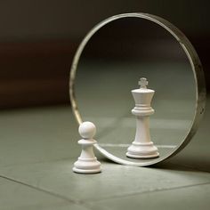 a white chess piece sitting in front of a mirror