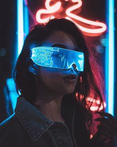 a woman wearing glowing glasses in front of neon signs with the letter s on it