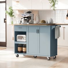 a blue kitchen cart with coffee maker on top in the middle of a white kitchen