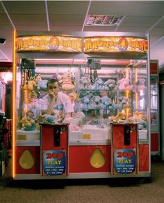 a man sitting in front of a machine with stuffed animals on it's sides