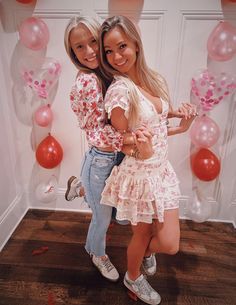 two young women standing next to each other in front of balloons and confetti