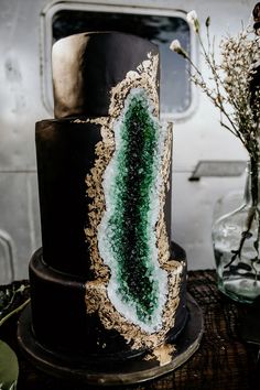 a black and gold cake with green frosting on the top is sitting on a table