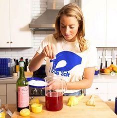 a woman in a white shirt is making some fruit juice