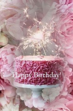 a birthday cake with pink flowers and sparklers in the air on it's side