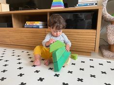 a little boy playing with wooden blocks on the floor