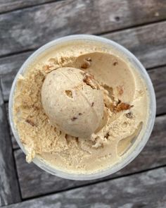 a scoop of ice cream in a plastic container on a wooden table with wood planks