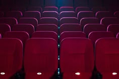 rows of red seats in an empty theater or movie theatre with blue light coming from the ceiling