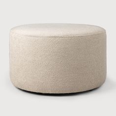 a white round ottoman sitting on top of a floor