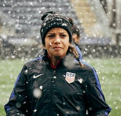 a woman standing in the snow wearing a black jacket