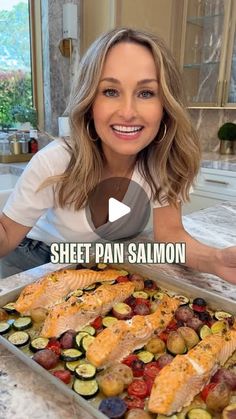 a woman is holding up a sheet pan salmon dish