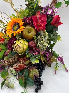 an arrangement of flowers, fruit and leaves on a white background