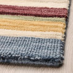 a multicolored rug is laying on the floor next to a wood flooring board