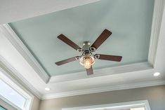 a ceiling fan is mounted to the ceiling in a room with blue walls and white trim