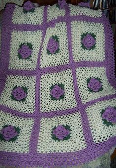 a crocheted blanket with purple flowers on it