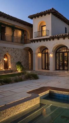 a large house with a pool in front of it at night, lit up by lights