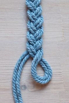 a blue rope is on top of a wooden table with a knot in the middle