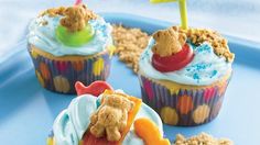 three cupcakes with frosting and teddy bears in them on a blue tray