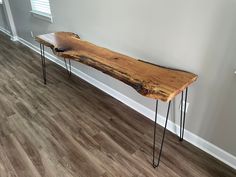 a wooden bench sitting on top of a hard wood floor next to a white wall