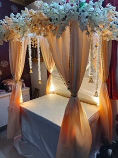 a bed with white flowers on top of it in a room filled with curtains and lights