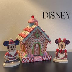 three mickey mouse figurines sitting on top of a table next to a house