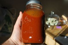 a hand holding a jar filled with red liquid