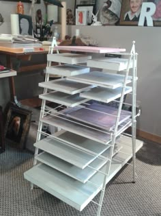 a stack of white shelves sitting on top of a carpeted floor next to a desk